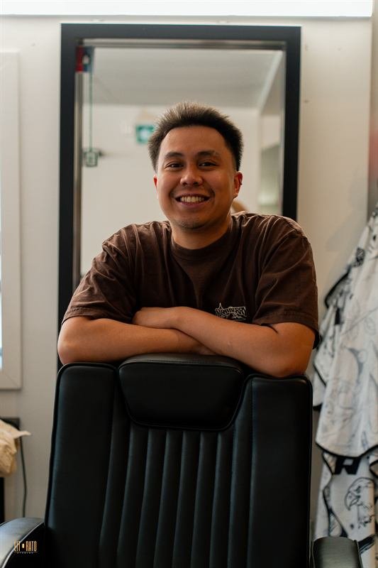 Ace, barber, smiling behind a barber chair